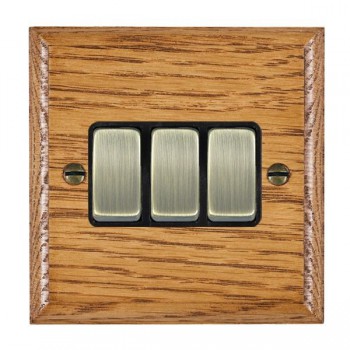 Hamilton Woods Ovolo Medium Oak 3 Gang 10AX 2 Way Switch with Antique Brass Rockers and Black Surround